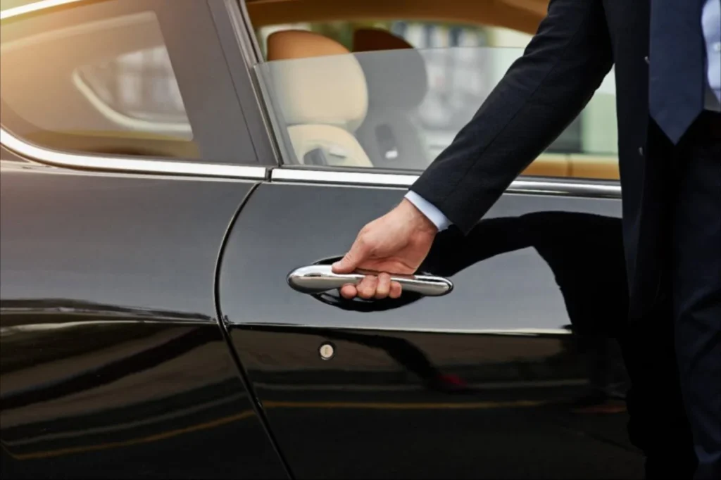 Private chauffeur opening a black car door